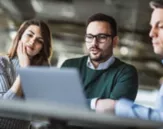 Three people looking at a computer